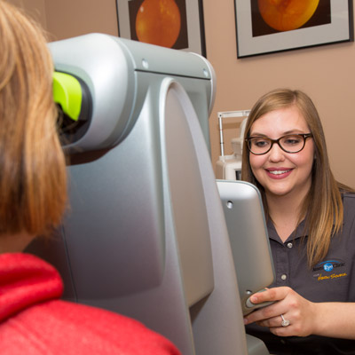 Smiling optometrician conducting an eye exam for a patient.